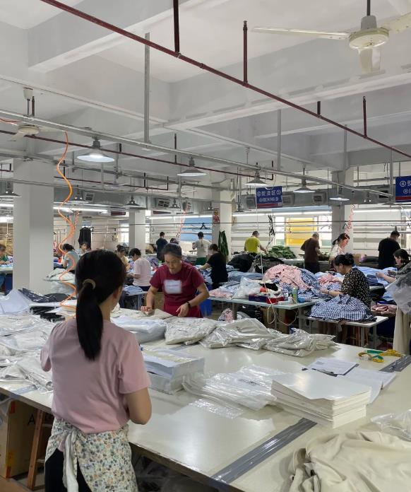 Workers folding and packing garments at workshop tables